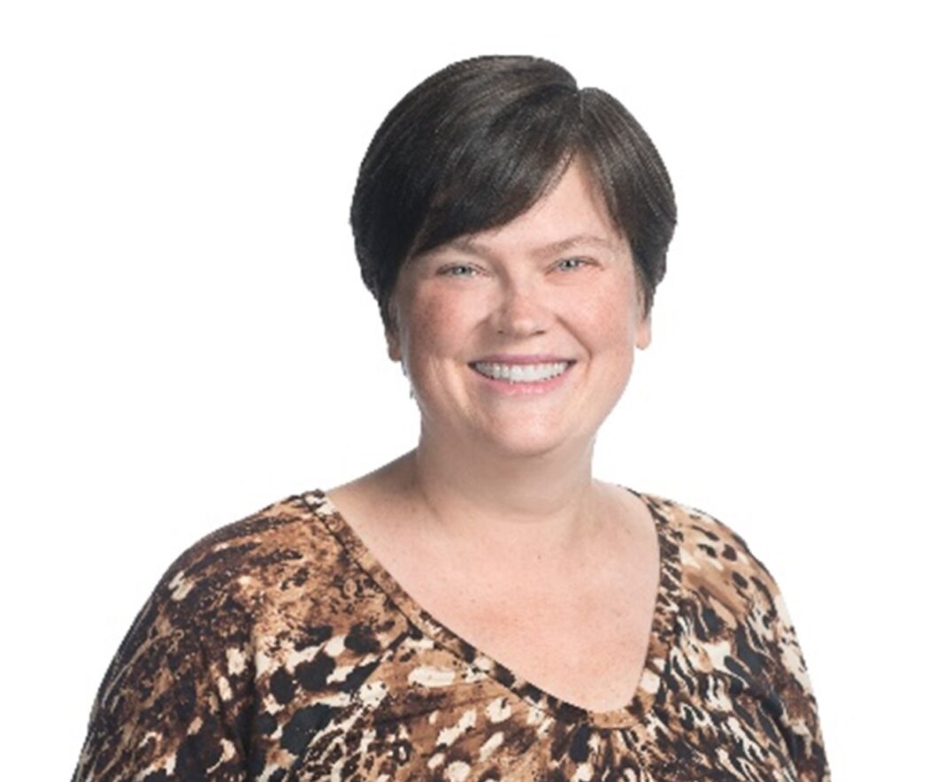 Amy Rankin has short brown hair parted on the left side. She wears a leopard print short-sleeved shirt.