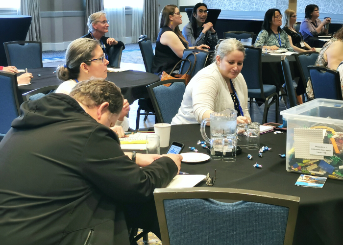 Delegates at the 2023 Saskatchewan Libraries Conference sit at tables and listen to a session speaker.