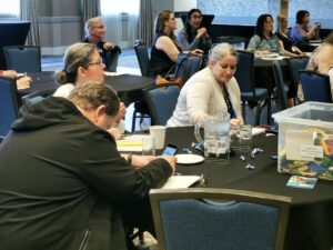 Delegates at the 2023 conference sit around tables as they listen to a presenter give a session.