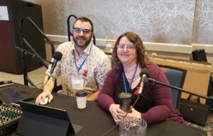 Brendan Dickie and Raylee Perkins sit behind a table as they host a conference session titled "QueerEd: Is Your Library Queered?"